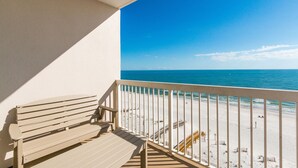 Un balcon avec un banc en bois donnant sur une plage.