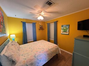 A bedroom with a bed, a ceiling fan, a painting, a television, and a dresser. - 2 Bedroom, Across the street from the beach! & Pup-Friendly! (Gulf Shores)