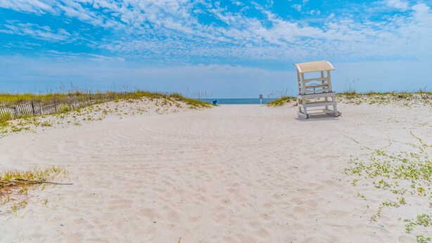 A beach with a lifeguard chair and a clear view of the ocean. - 2 Bedroom, Across the street from the beach! & Pup-Friendly! (Gulf Shores)