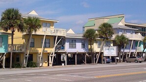 A row of colorful buildings with balconies, a sign for 'Paradise Isle', and palm trees lining the street. - 2 Bedroom, Across the street from the beach! & Pup-Friendly! (Gulf Shores)