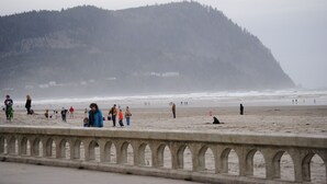 Ein Strand mit Menschen und einer Steinmauer im Vordergrund.