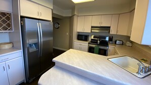 A modern kitchen with white cabinets, stainless steel appliances, a built-in oven, microwave, and a sink. - Great location, quick drive to Snowbird Alta, Brighton Solitude, walk to dinner (Cottonwood Heights)