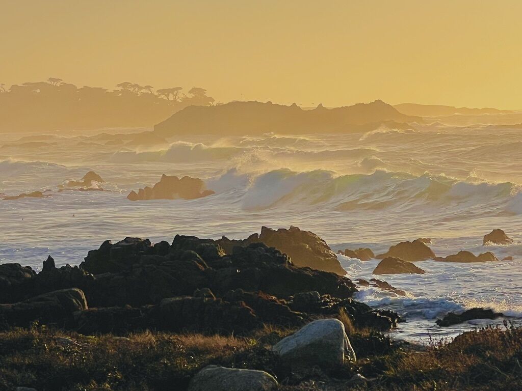Un paysage côtier caractérisé par un terrain rocheux et des vagues qui déferlent sur le rivage.
