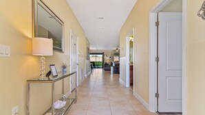 A hallway with a glass console table, a mirror, and a door leading to a kitchen area. - ⭐⭐⭐⭐⭐Oversize Private Pool & Spa, Free Pool Heat, Exclusive Luxury Platinum Home (Davenport)