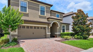 A two-story house with a beige facade, a garage, and a brick driveway. - ⭐⭐⭐⭐⭐Oversize Private Pool & Spa, Free Pool Heat, Exclusive Luxury Platinum Home (Davenport)