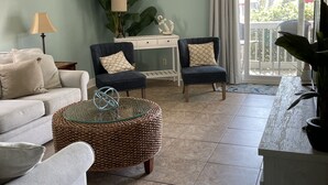 Una sala de estar con un sofá, dos sillones, una mesa de centro y un comedor con mesa y sillas.