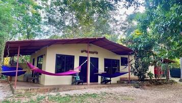 A single-story building with a covered porch, two hammocks, and a small outdoor seating area.