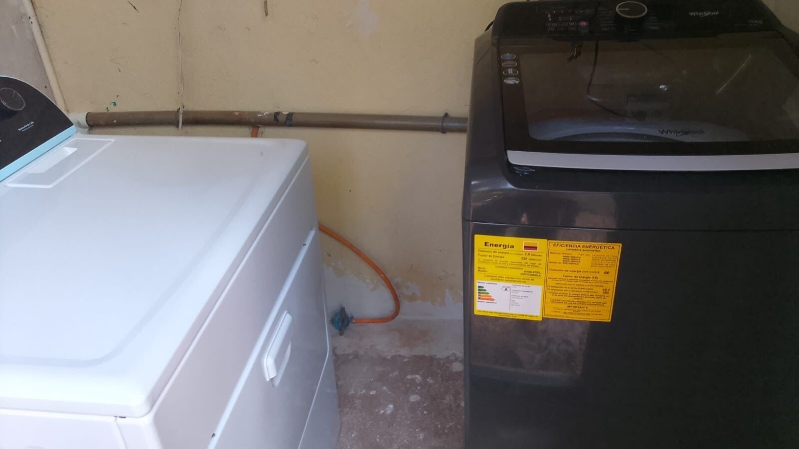 Una lavadora blanca y un secadora negra, colocadas una al lado de la otra, con una etiqueta amarilla de eficiencia energética en la secadora.