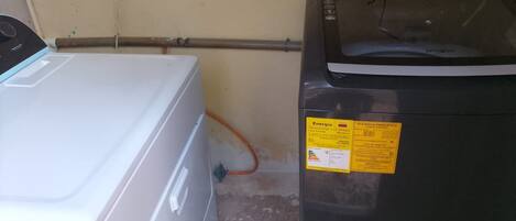 Una lavadora blanca y un secadora negra, colocadas una al lado de la otra, con una etiqueta amarilla de eficiencia energética en la secadora.