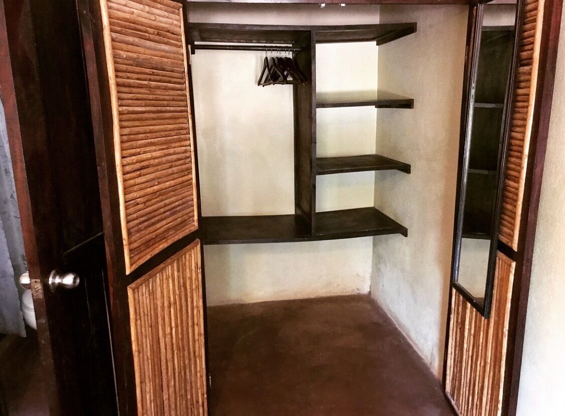 A walk-in closet with wooden paneling, a hanging rack, and three shelves.
