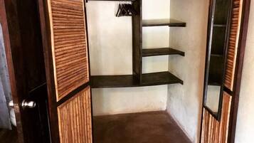 A walk-in closet with wooden paneling, a hanging rack, and three shelves.