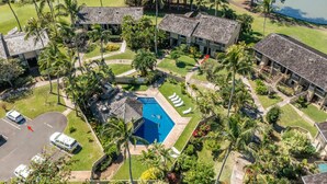 An aerial view of a resort with multiple buildings, a swimming pool, and palm trees.