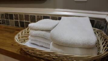 A wicker basket filled with neatly folded white towels on a wooden countertop.