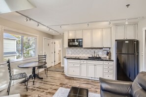 A modern kitchen with white cabinets, a black refrigerator, and a dining area with a table and chairs. - Downtown Boulder Guest House for 2 guests (Boulder)