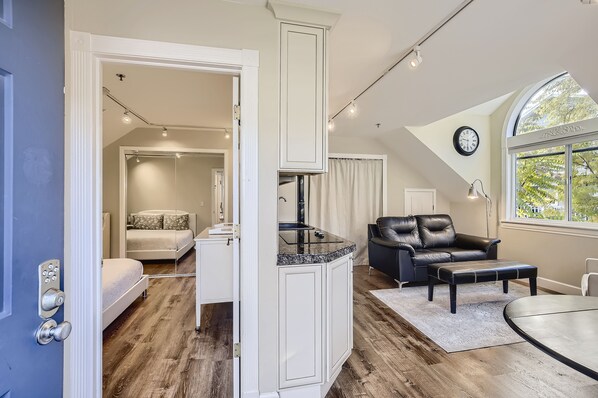 A spacious room with a large window, a dining table, a leather sofa, and a built-in kitchen area. - Downtown Boulder Guest House for 2 guests (Boulder)