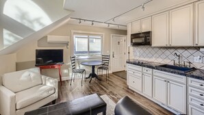 A compact kitchen with white cabinets, a black countertop, and a built-in microwave. - Downtown Boulder Guest House for 2 guests (Boulder)