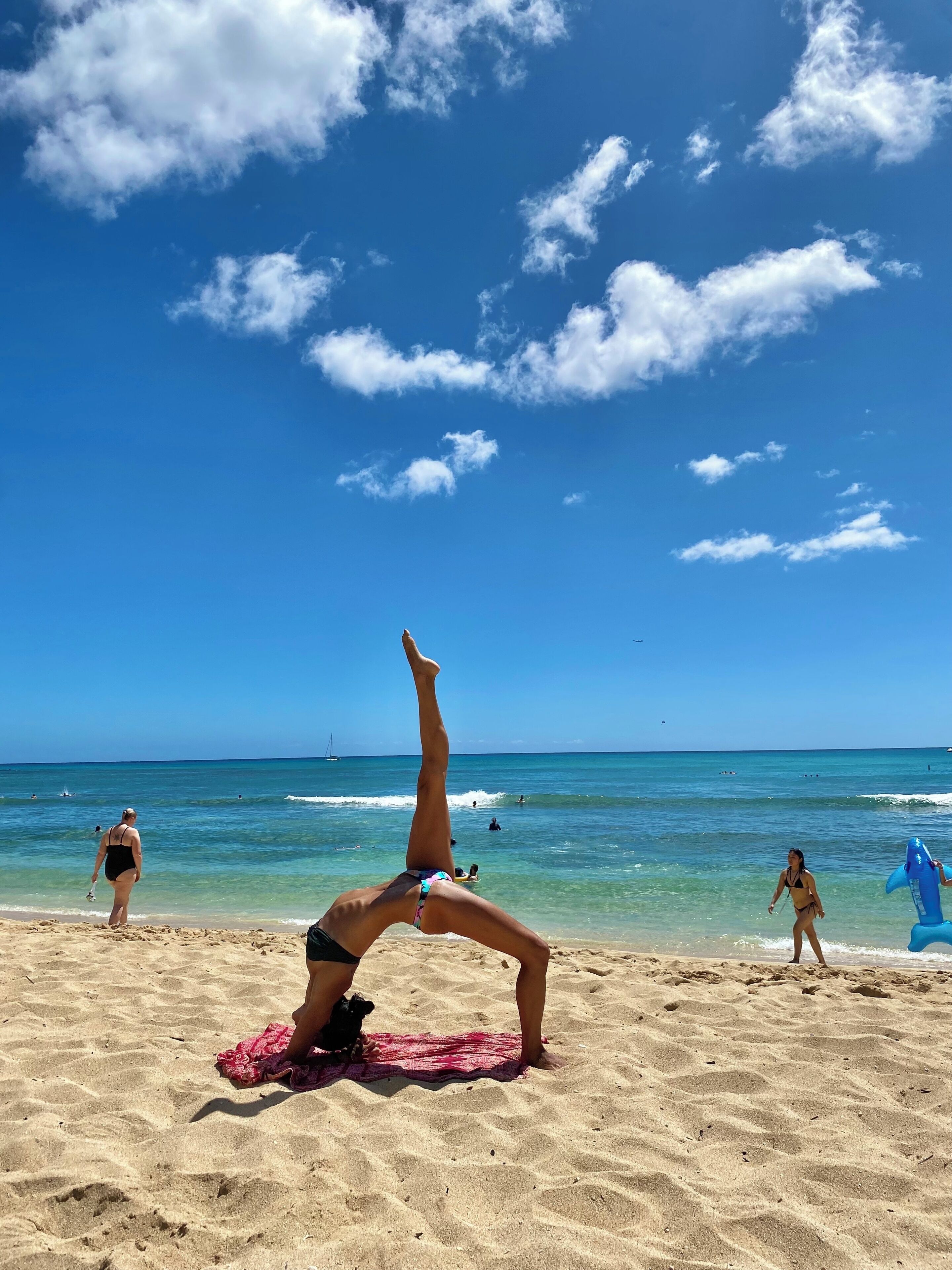 Une scène de plage, avec un ciel dégagé et une personne pratiquant une posture de yoga sur une serviette.
