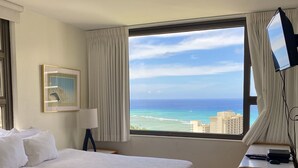 A hotel room with a large bed, a desk with a lamp, and a view of the ocean. - Deluxe 34th floor Waikiki Banyan Epic Ocean View, 5min from Waikiki Beach (Waikiki)