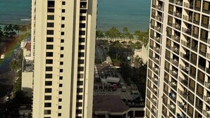 Un immeuble de grande hauteur doté de nombreux balcons, offrant une vue dégagée sur l’océan et permettant d’apercevoir un arc-en-ciel.