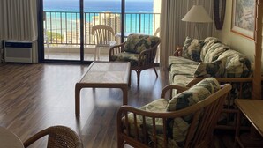 Une pièce avec vue sur l’océan, comprenant un canapé, un fauteuil, une table et une lampe.