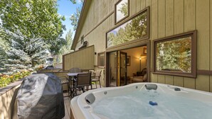 Ein Whirlpool in einem Hinterhof mit überdachtem Grill, einem Patio-Tisch und Stühlen.