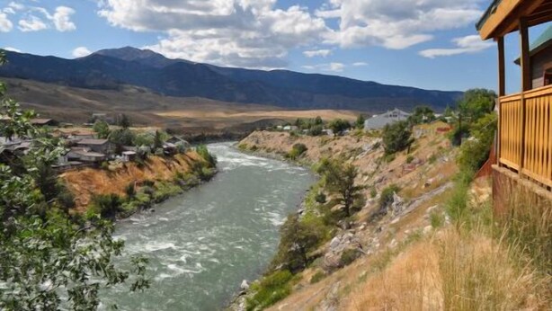 A river flowing through a mountainous landscape with a wooden structure on the right. - Cozy Eagles Nest Cabin Above the River! 6 Blocks from Yellowstone Park  (Gardiner)