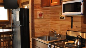 A compact kitchen with wooden walls, a stainless steel refrigerator, a microwave, a stove, and a sink. - Cozy Eagles Nest Cabin Above the River! 6 Blocks from Yellowstone Park  (Gardiner)