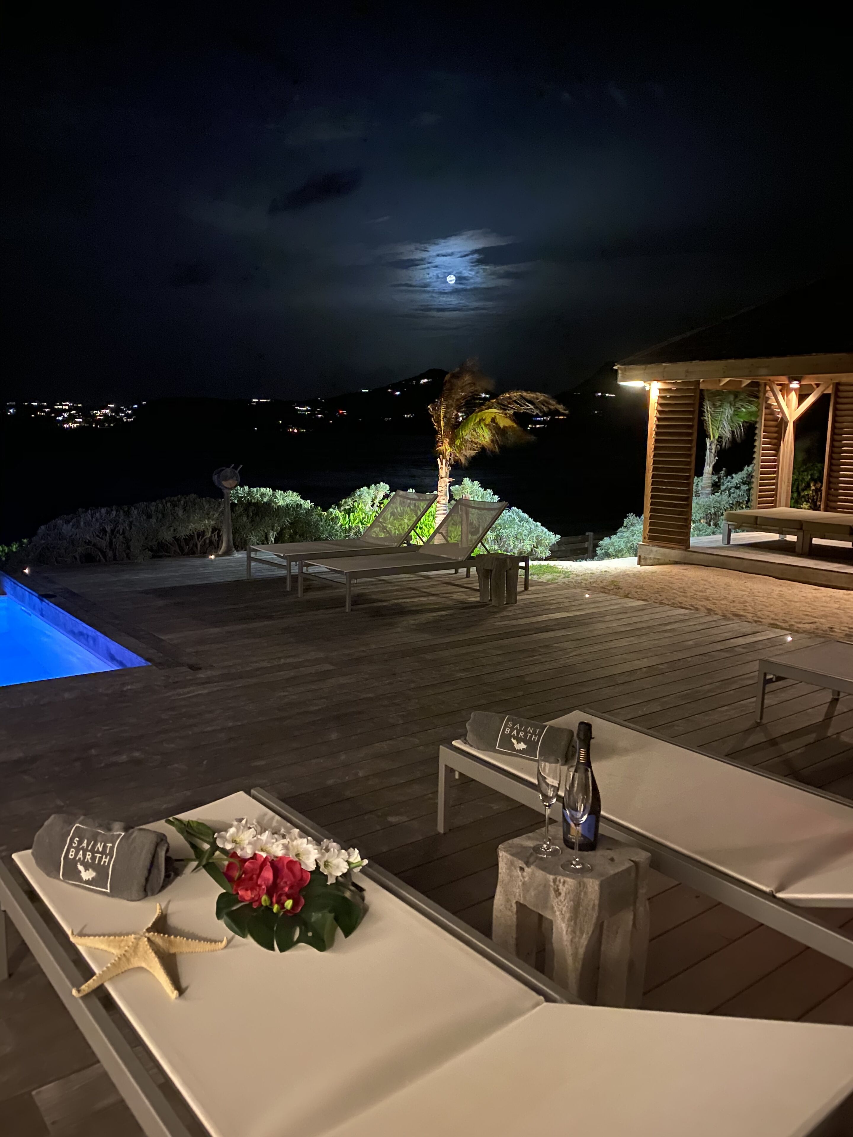 A wooden deck with a pool, lounge chairs, and a table set for dining.