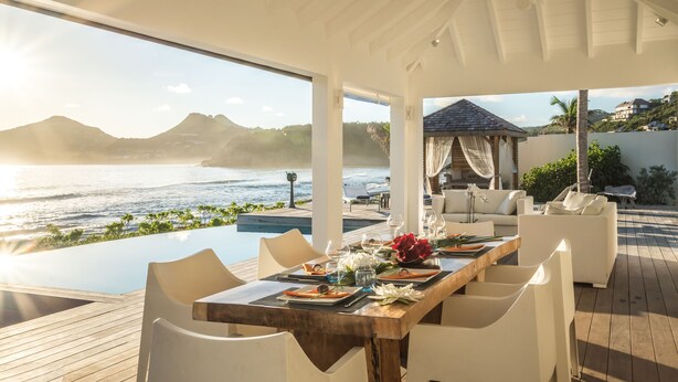 Un área de comedor al aire libre techada, con vistas al mar y a las montañas.