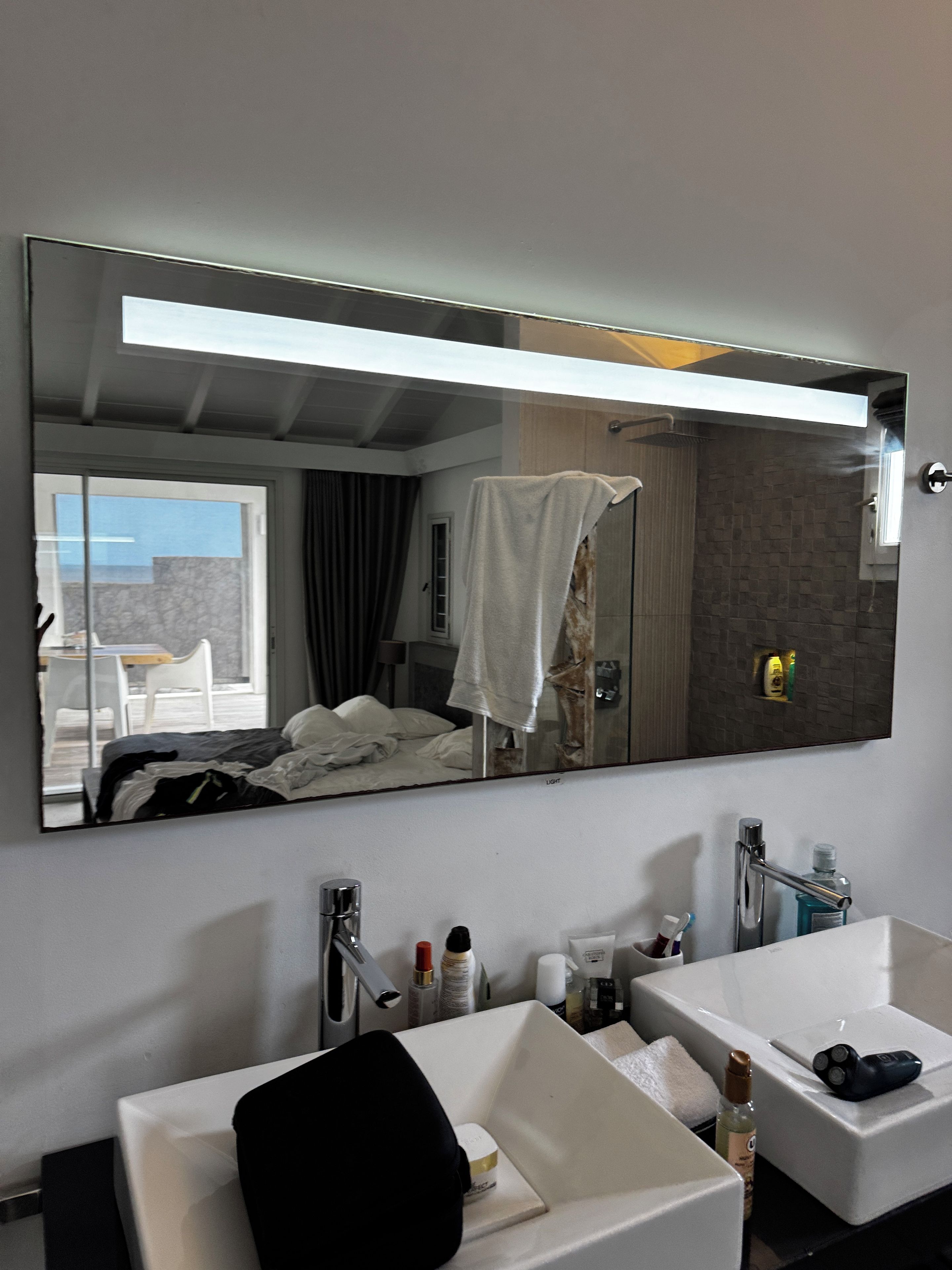 Une salle de bain avec un grand miroir, deux lavabos et une douche.