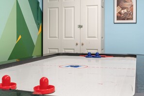 A room with a white door, a green wall with a geometric pattern, and a table hockey game. - STUNNING CABIN, TROUT STREAM, HUGE GAMEROOM, HOT TUB,FIRE PIT,TUBING,& MEMORIES! (Cosby)