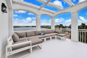 A white outdoor seating area with a view of the water and buildings.