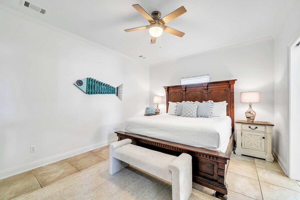 Une chambre à coucher comprenant un lit, un ventilateur de plafond, une table de chevet, un banc et un décor mural représentant des poissons.
