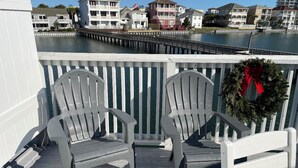 A wooden deck with two Adirondack chairs and a wreath. - 4 Min Walk to Beach and Lakefront Patio! Patio + Community Pool! (Destin)