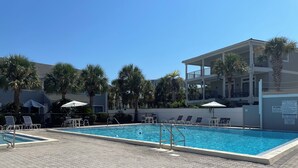 A swimming pool with lounge chairs and umbrellas, surrounded by palm trees and a multi-story building. - 4 Min Walk to Beach and Lakefront Patio! Patio + Community Pool! (Destin)