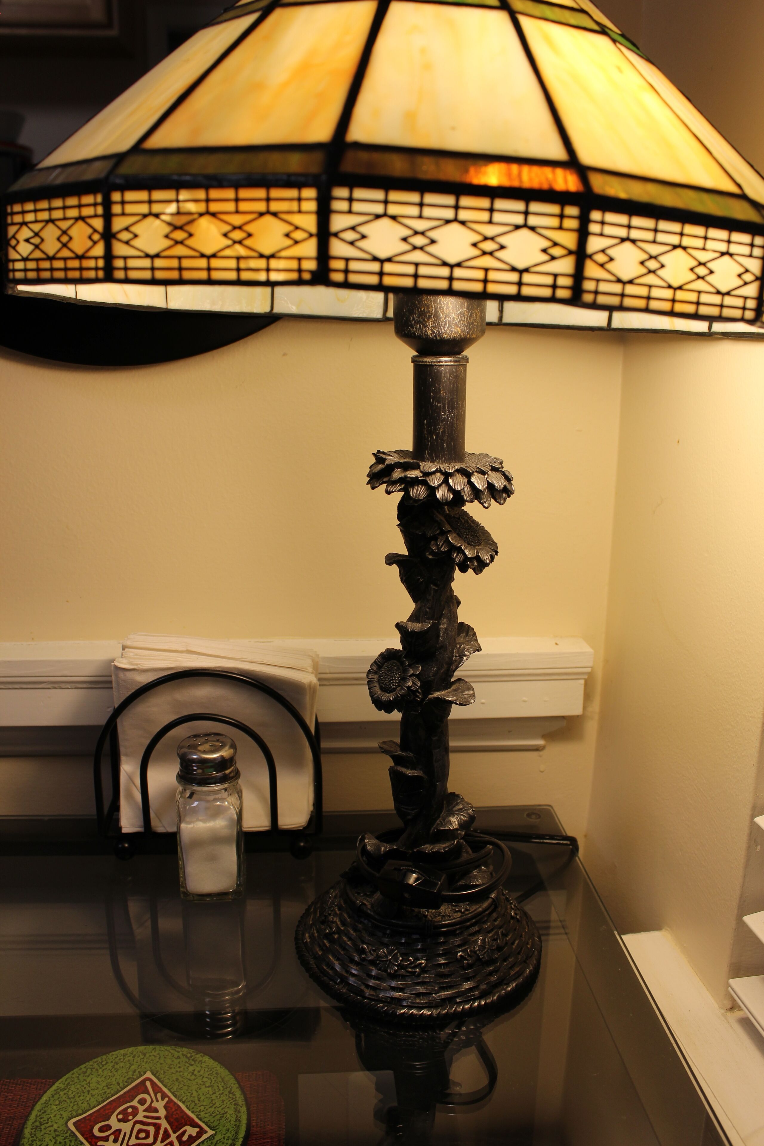 Un tavolo con una lampada decorativa, posacenere e un sottopiattino verde.
