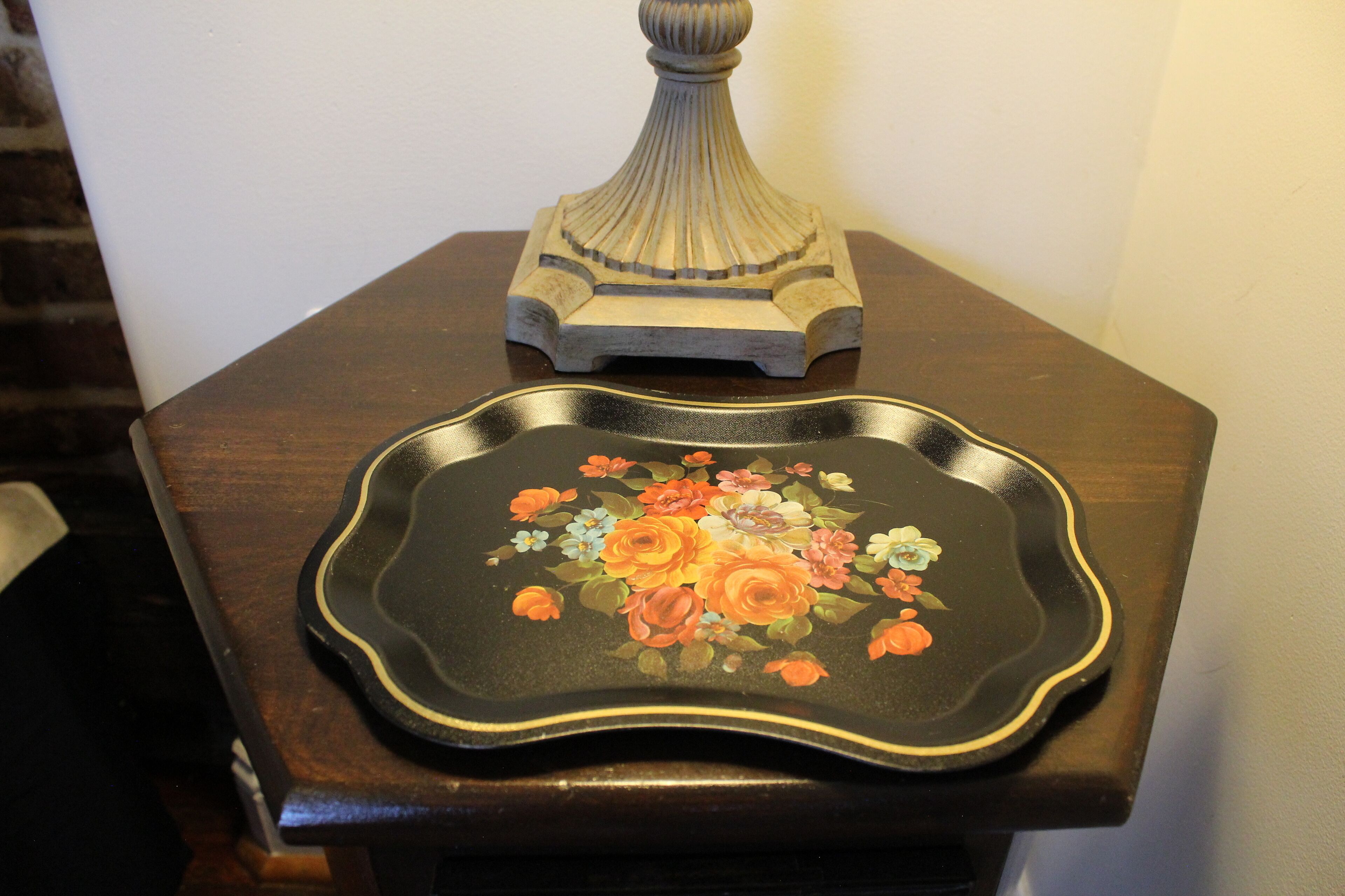 Una mesa de madera oscura con una bandeja decorativa con diseño floral.