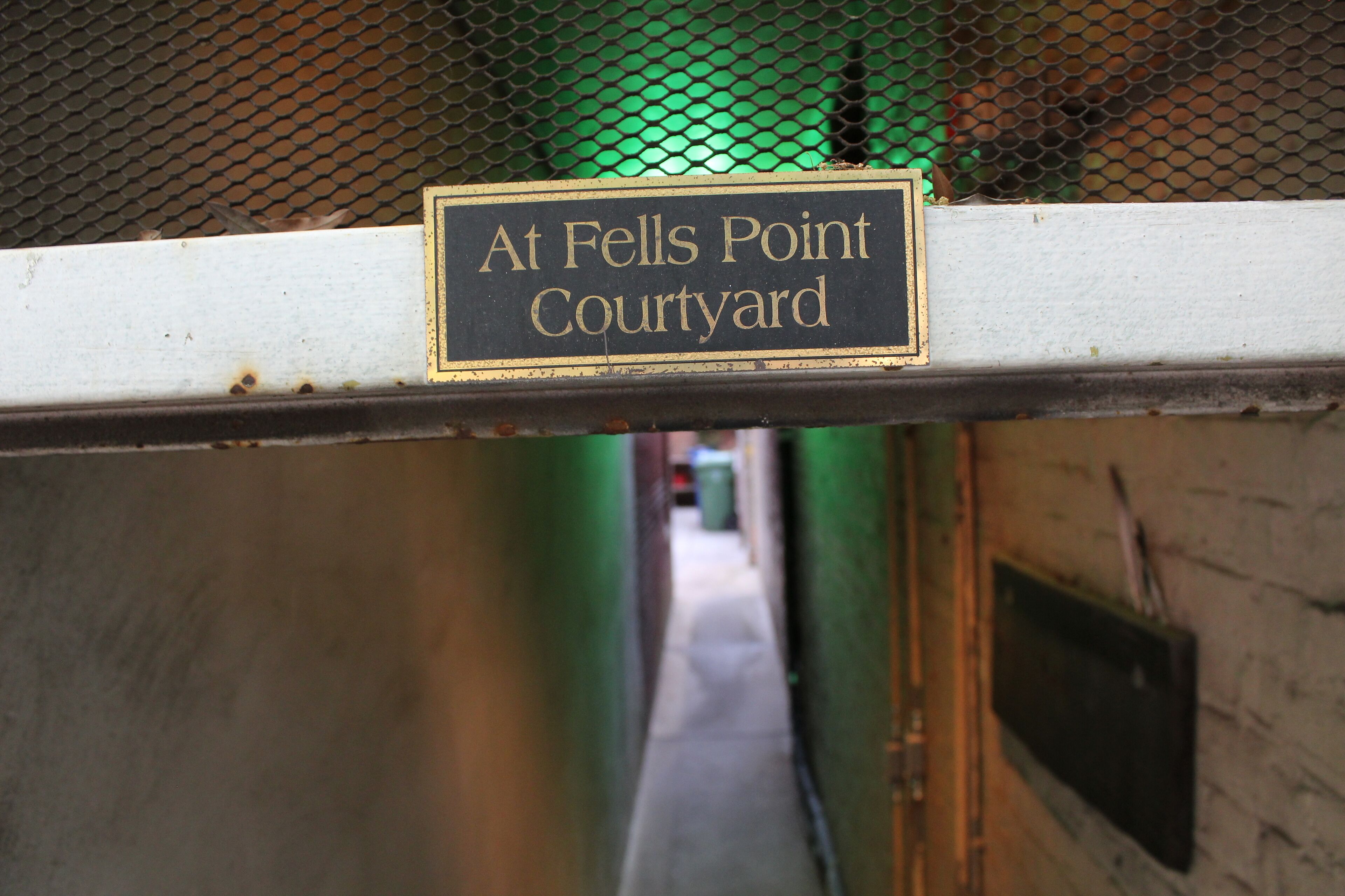 Une pancarte indiquant « Au Fells Point Courtyard » est fixée à une structure métallique.