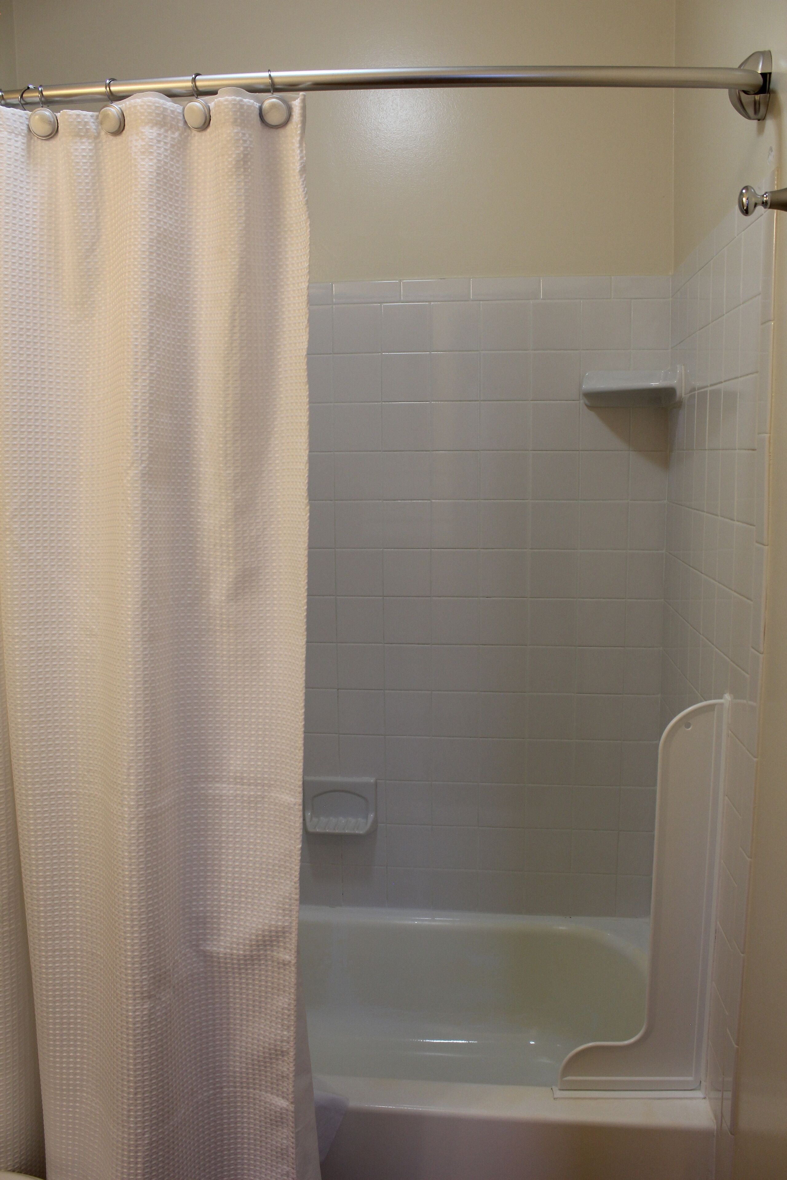 A bathroom with a bathtub, a shower curtain, and white tiled walls.