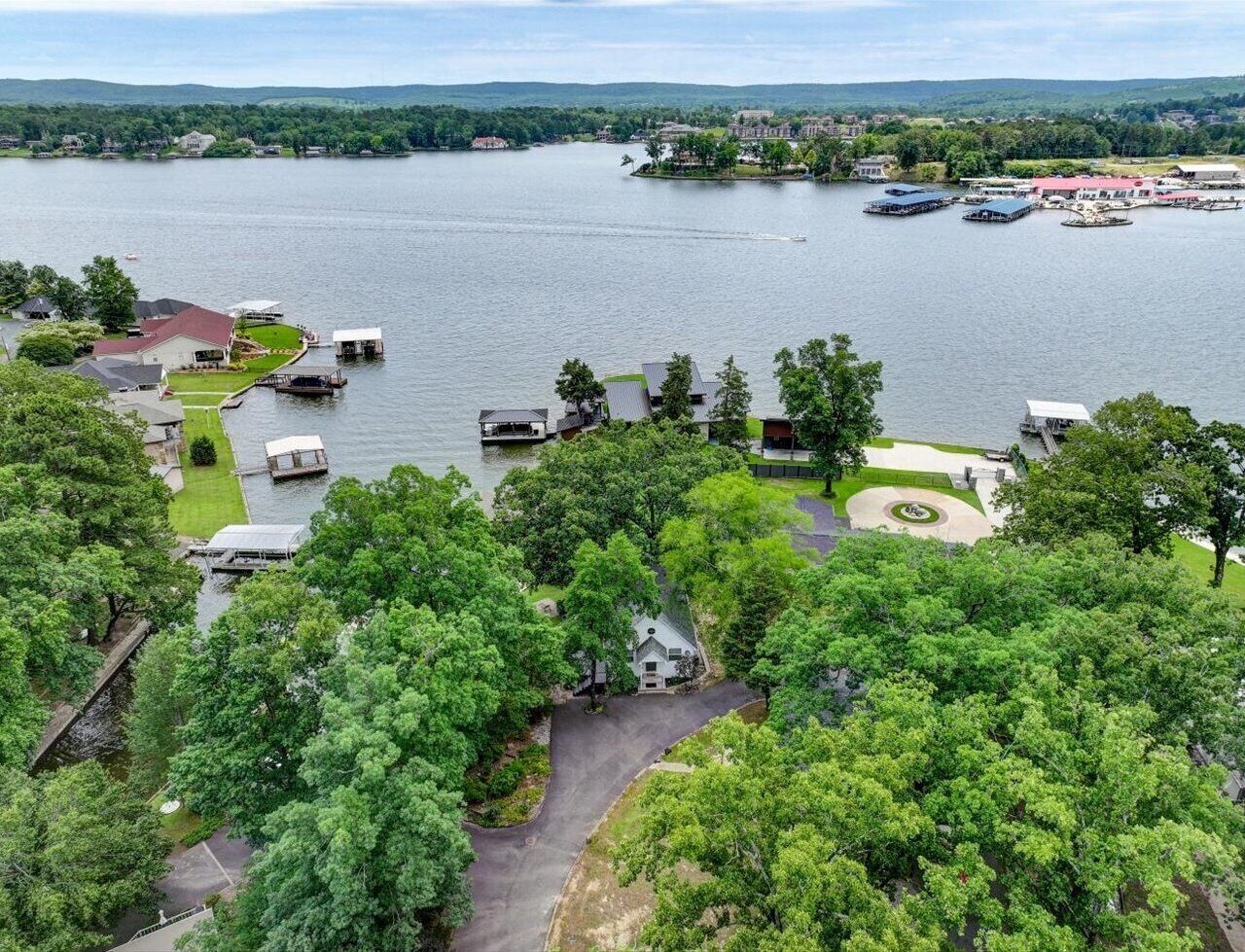 A lakeside property with boats docked, a small house, and a well-maintained lawn.