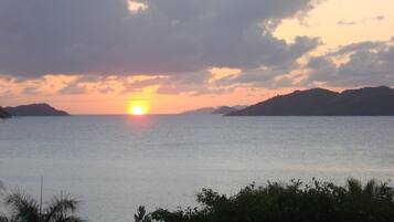 A sunset over a calm sea with distant landforms.