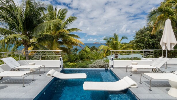 Une piscine avec des chaises longues et vue sur l’océan.