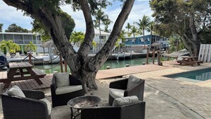 Ein Poolbereich mit Korbmöbeln, einer Feuerstelle und Blick auf den Yachthafen.