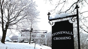 A snow-covered road with a sign reading "STONEWALL CROSSING".