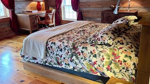 A cozy log cabin bedroom with a wooden bed, a desk, and a chair.