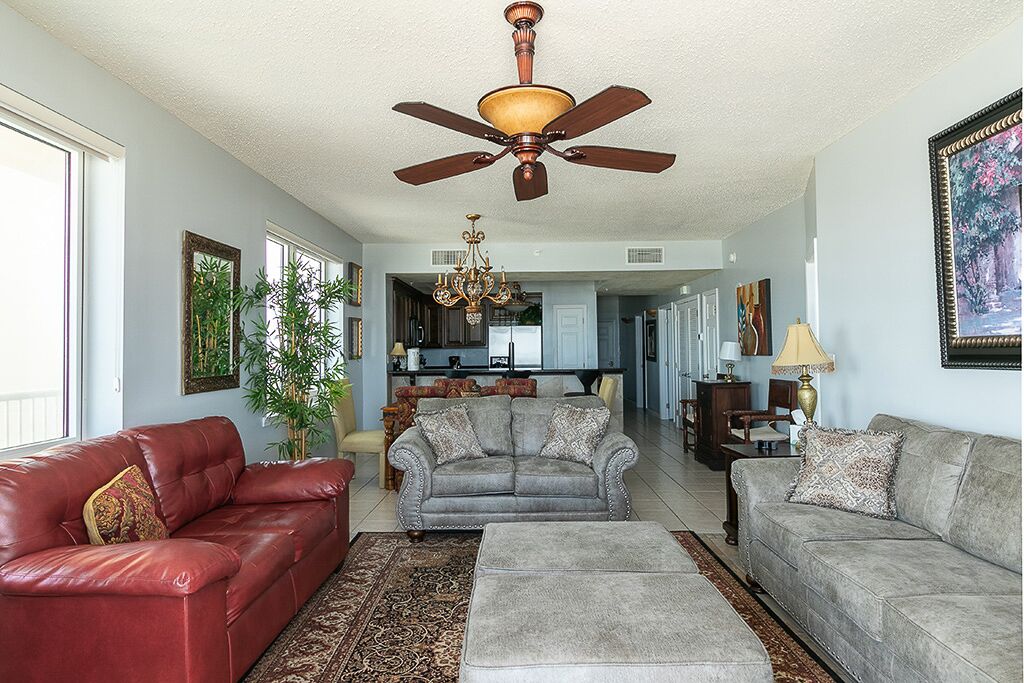 A spacious living room with a ceiling fan, two sofas, a coffee table, and a chandelier.