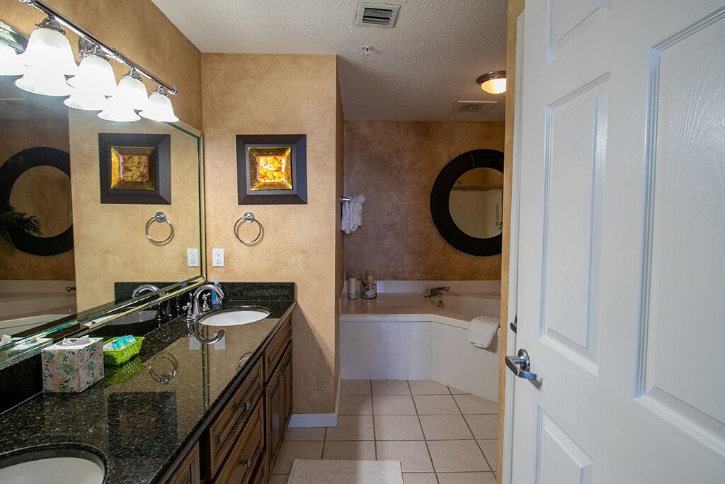 A bathroom with a large mirror, a sink, a bathtub, and a toilet.