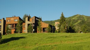 Un ensemble immobilier moderne composé de plusieurs bâtiments, entouré d’une zone verdoyante et situé dans un paysage vallonné.