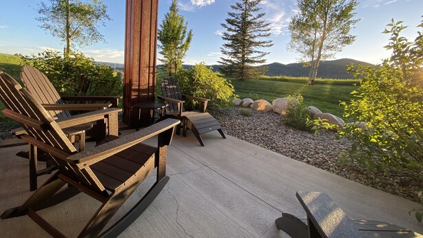 Une terrasse extérieure avec des fauteuils Adirondack, une table et un banc.