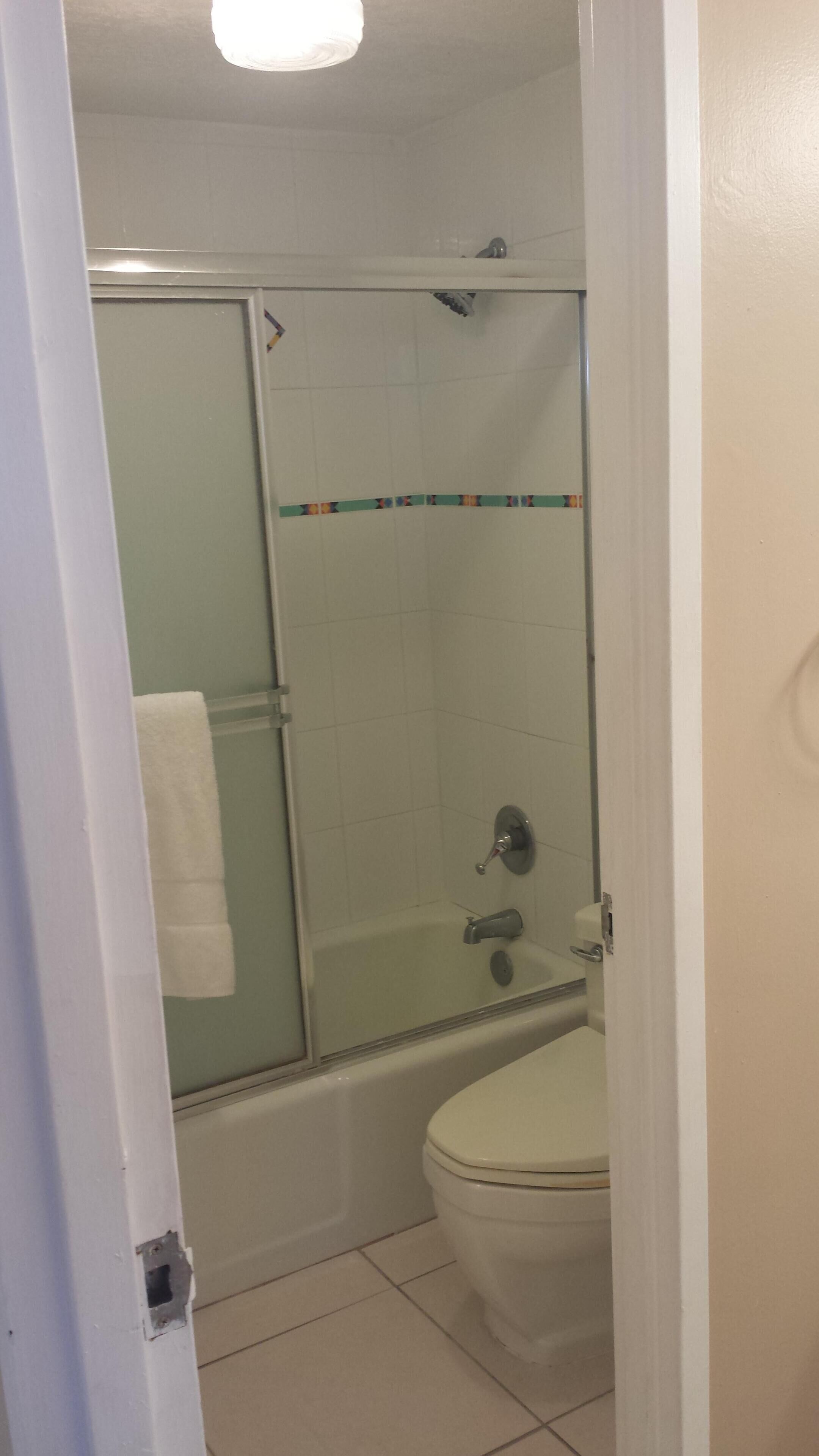 A bathroom with a glass-enclosed shower, a white toilet, and a bathtub.